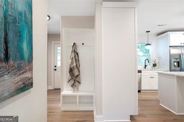 hallway featuring light wood-type flooring, visible vents, and a sink