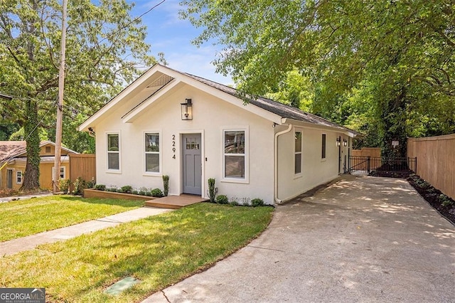 bungalow with a front yard, fence, and stucco siding