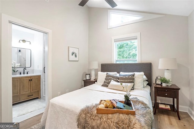 bedroom with connected bathroom, light wood-style flooring, a ceiling fan, baseboards, and vaulted ceiling