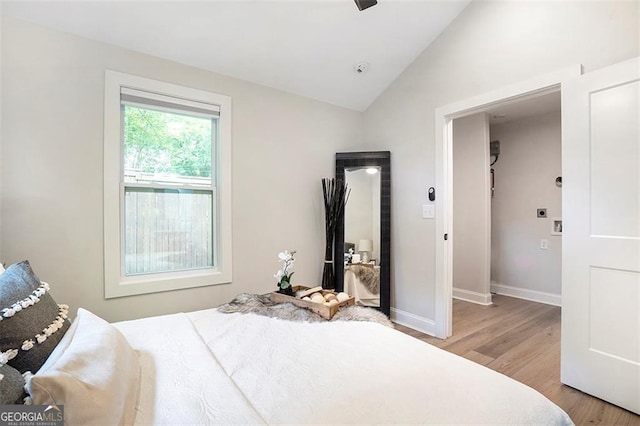 bedroom featuring baseboards, vaulted ceiling, and wood finished floors