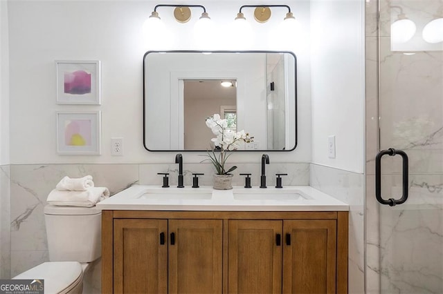 bathroom featuring toilet, a marble finish shower, a sink, and tile walls