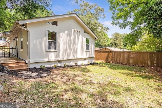 view of side of home with fence private yard, crawl space, and a yard