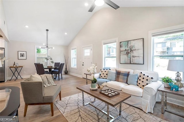 living room featuring high vaulted ceiling, recessed lighting, light wood-style flooring, and baseboards