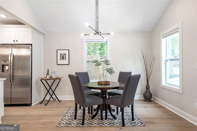 dining room featuring a chandelier, lofted ceiling, a healthy amount of sunlight, and light wood-style flooring