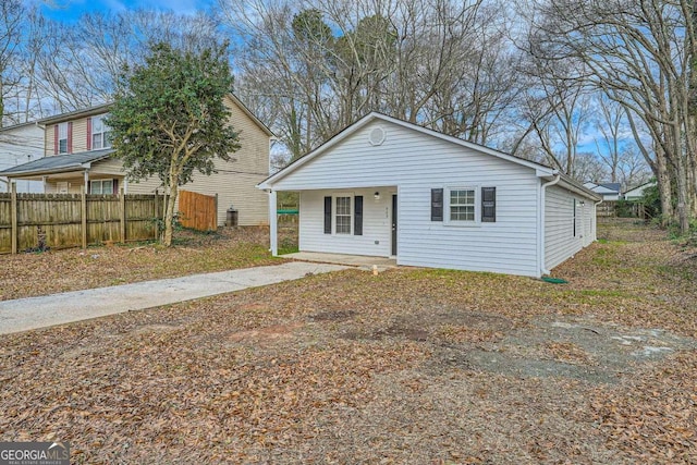 view of front of home featuring covered porch, concrete driveway, and fence