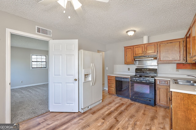 kitchen featuring black appliances, a sink, light countertops, and under cabinet range hood