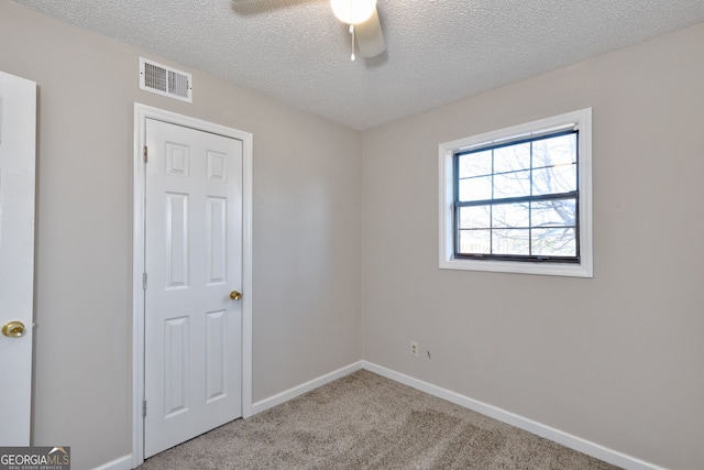 spare room featuring visible vents, light carpet, ceiling fan, a textured ceiling, and baseboards