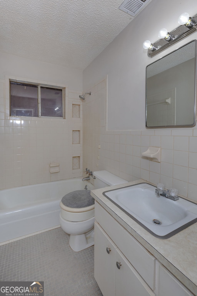 bathroom featuring toilet, tile patterned flooring, bathtub / shower combination, a textured ceiling, and tile walls