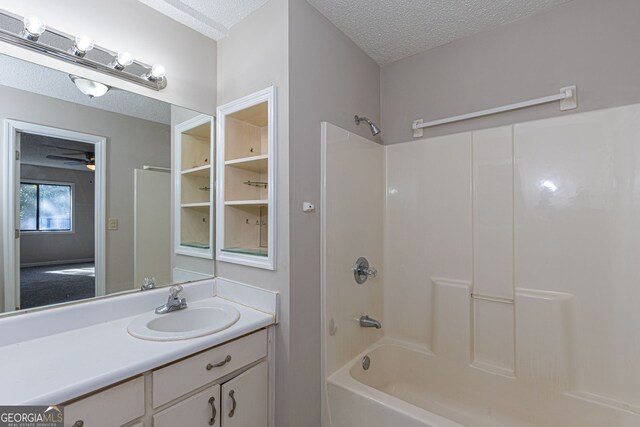 bathroom with bathtub / shower combination, ceiling fan, a textured ceiling, and vanity