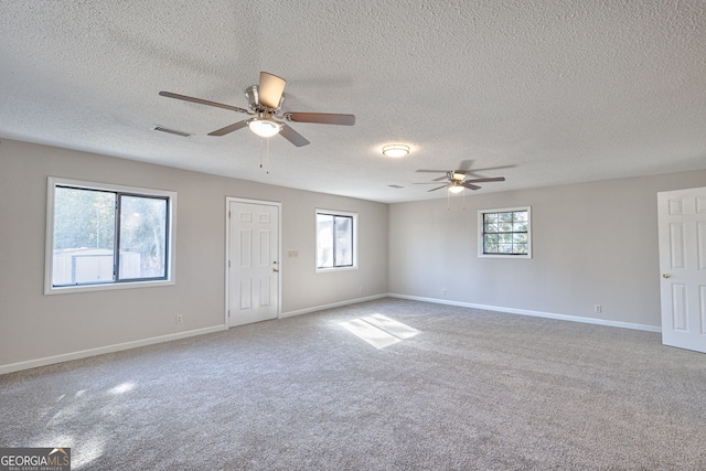 unfurnished room with visible vents, baseboards, ceiling fan, carpet, and a textured ceiling