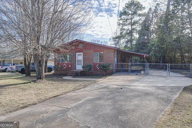 view of front facade featuring an attached carport, brick siding, fence, driveway, and a gate