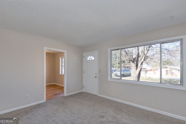 foyer with light carpet, a textured ceiling, and baseboards