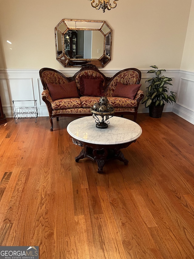 sitting room featuring wainscoting, a decorative wall, and wood finished floors