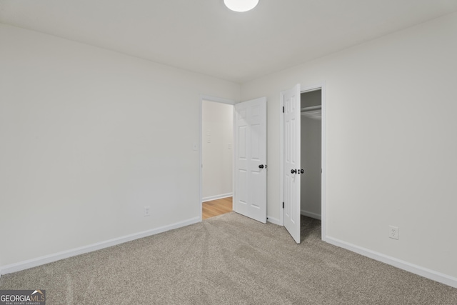 unfurnished bedroom featuring a closet, light carpet, and baseboards
