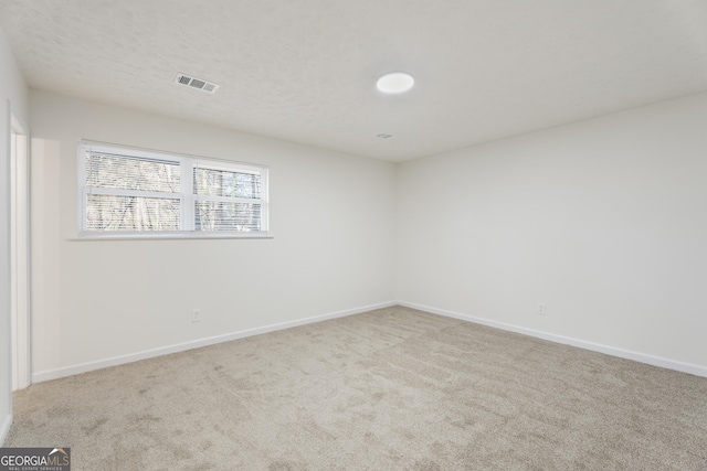 empty room featuring baseboards, a textured ceiling, visible vents, and light colored carpet