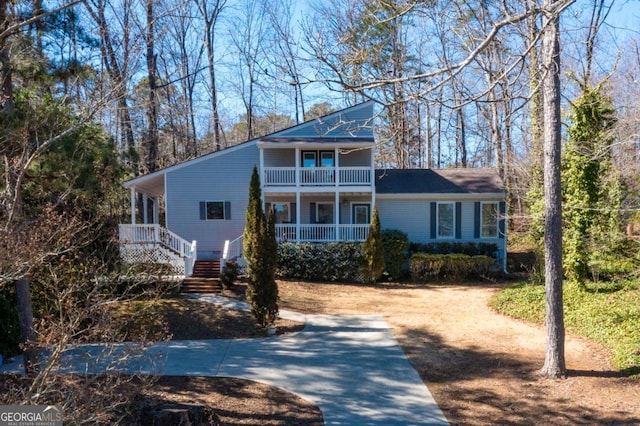 view of front of property with a balcony, driveway, stairs, and a porch