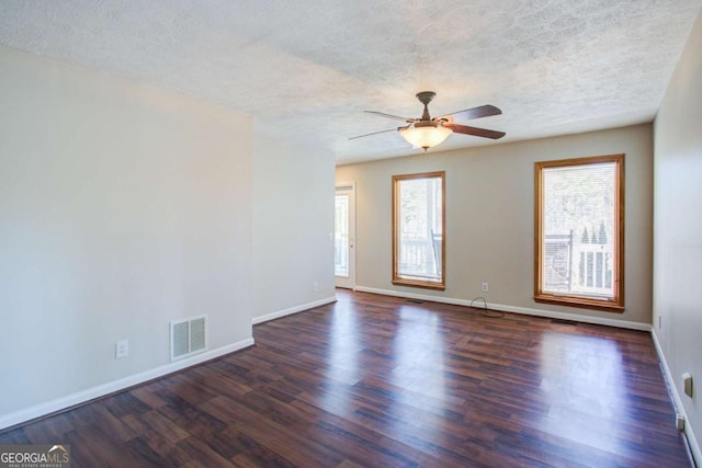 spare room featuring dark wood-style flooring, visible vents, a textured ceiling, and baseboards