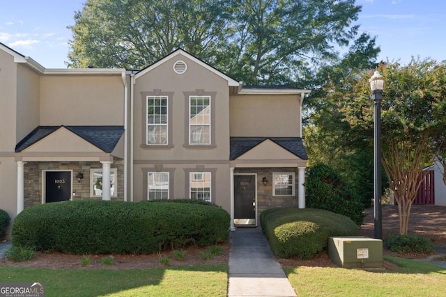 view of property with stone siding, a front lawn, and stucco siding