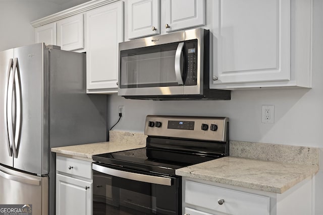 kitchen with stainless steel appliances, light stone countertops, and white cabinets