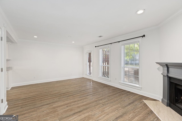 unfurnished living room with baseboards, a fireplace with flush hearth, ornamental molding, and wood finished floors