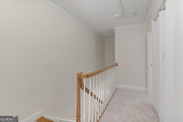 hall featuring crown molding, light colored carpet, attic access, an upstairs landing, and baseboards