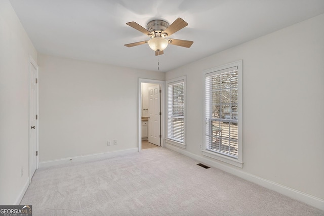 empty room with visible vents, baseboards, ceiling fan, and light colored carpet