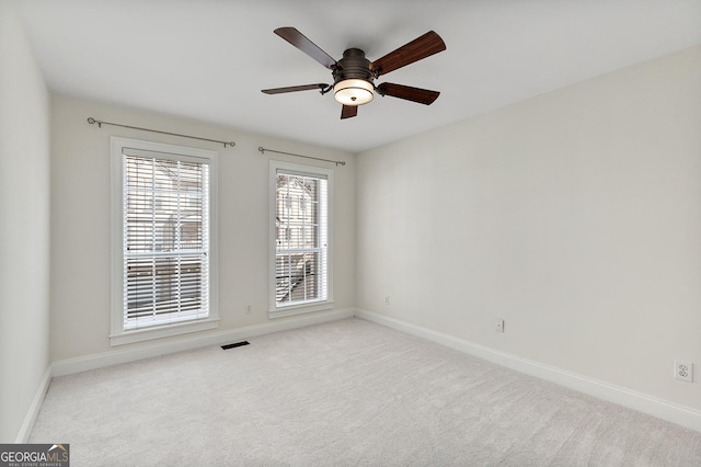 spare room with visible vents, baseboards, a ceiling fan, and light colored carpet