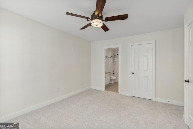 unfurnished bedroom featuring light carpet, ensuite bath, baseboards, and a ceiling fan