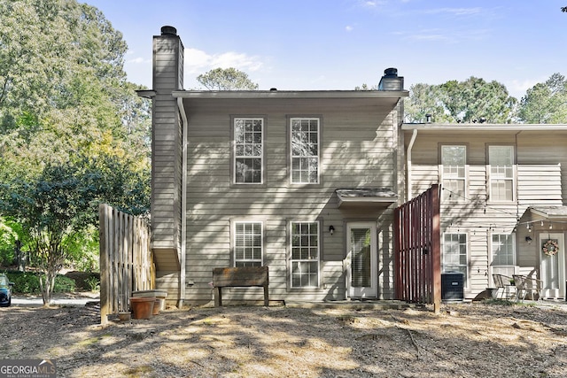 back of house featuring central AC and a chimney