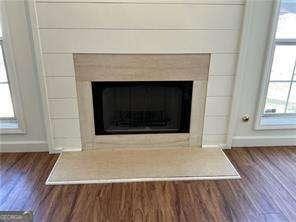 details featuring baseboards, a tiled fireplace, and wood finished floors