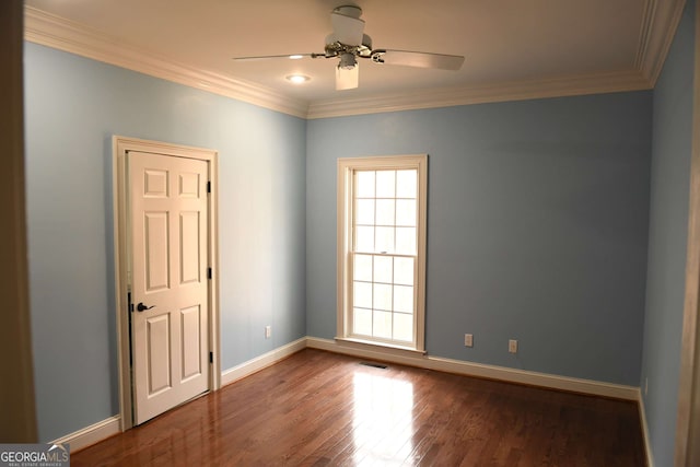 spare room with dark wood-type flooring, visible vents, ornamental molding, and baseboards