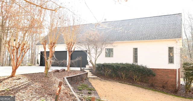 view of front of house with concrete driveway, brick siding, an attached garage, and a shingled roof