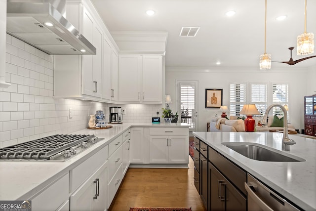 kitchen with visible vents, wall chimney exhaust hood, ornamental molding, stainless steel appliances, and a sink