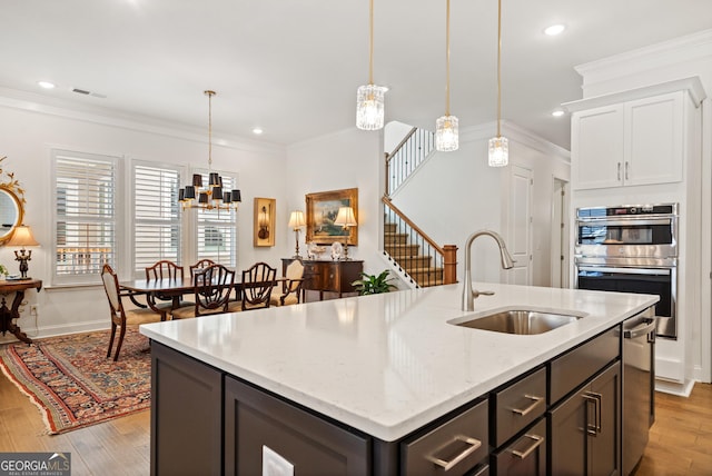 kitchen featuring crown molding, visible vents, double oven, light wood-style floors, and a sink