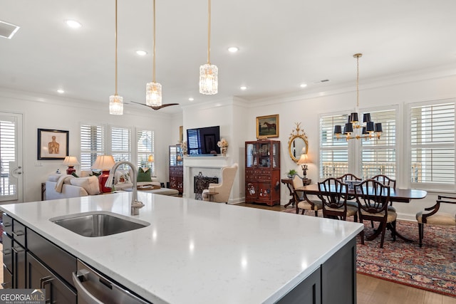 kitchen featuring crown molding, open floor plan, a fireplace, and a sink