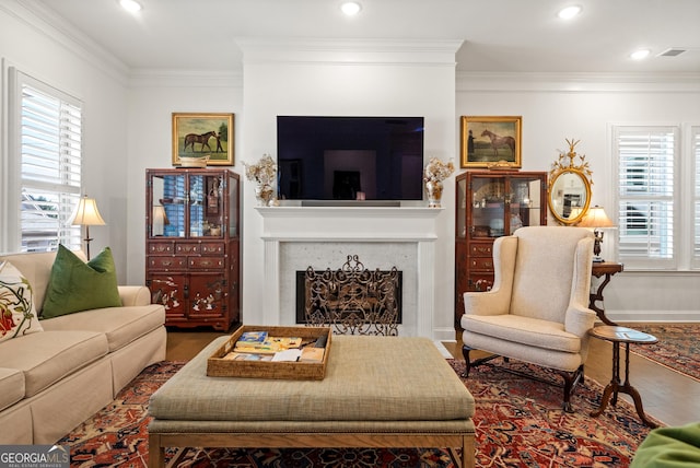 living room with a healthy amount of sunlight, a fireplace, ornamental molding, and wood finished floors