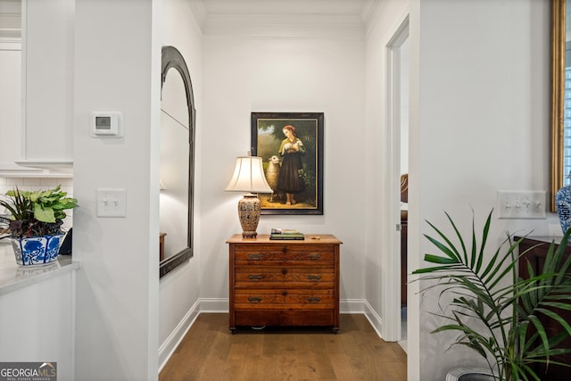 hallway with baseboards, ornamental molding, and wood finished floors