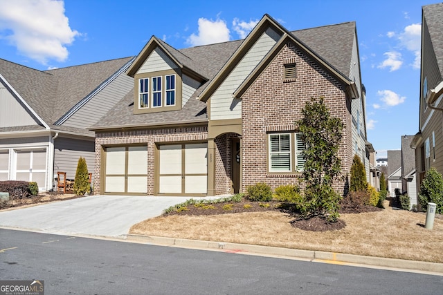 view of front of property featuring a garage, roof with shingles, concrete driveway, and brick siding