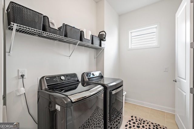 clothes washing area featuring laundry area, washer and clothes dryer, baseboards, and light tile patterned floors