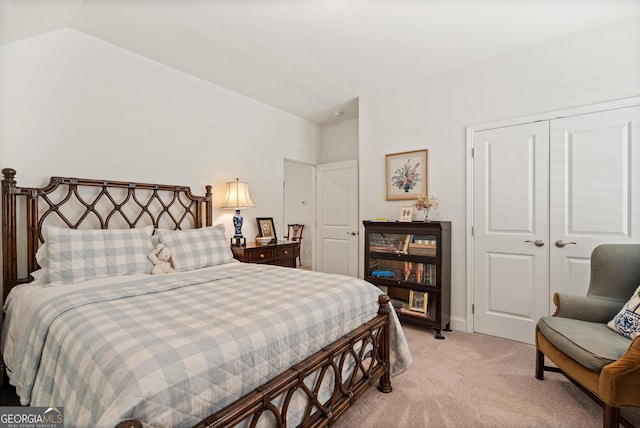 bedroom with a closet, light colored carpet, and vaulted ceiling