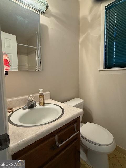 bathroom featuring tile patterned flooring, vanity, and toilet