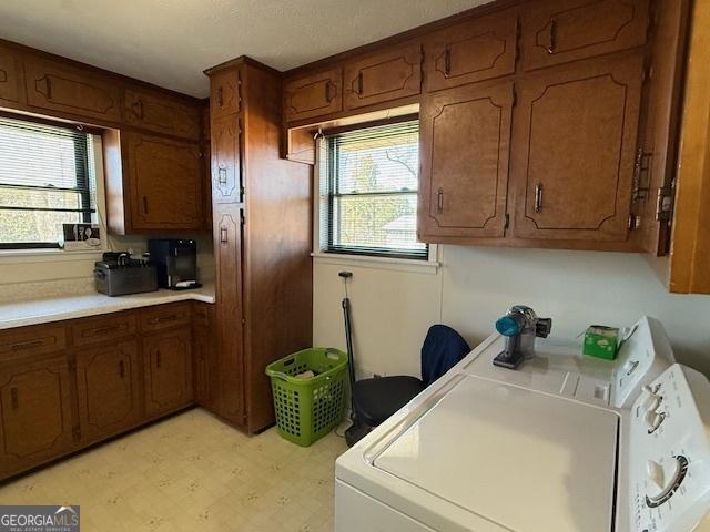 clothes washing area with light floors, a wealth of natural light, cabinet space, and washer and dryer