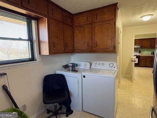 laundry room featuring light floors, cabinet space, a textured ceiling, washer and dryer, and baseboards