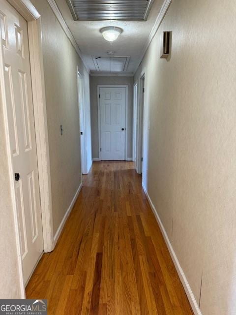 corridor with baseboards, visible vents, ornamental molding, and wood finished floors