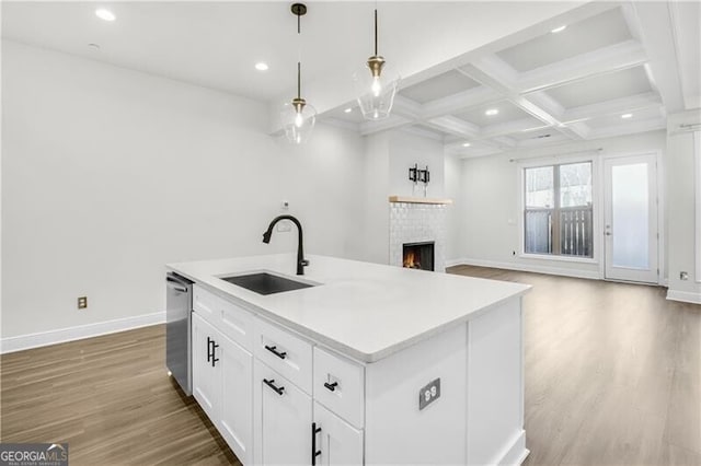 kitchen with dishwasher, coffered ceiling, a sink, and wood finished floors