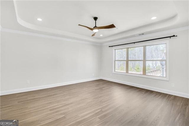 unfurnished room with baseboards, a tray ceiling, wood finished floors, and recessed lighting