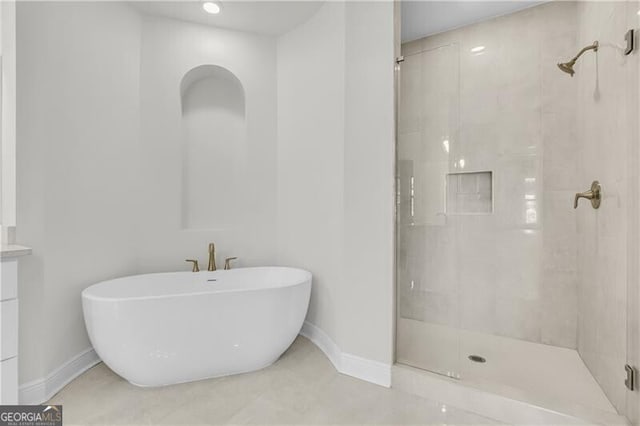 bathroom with a stall shower, a freestanding tub, vanity, and baseboards