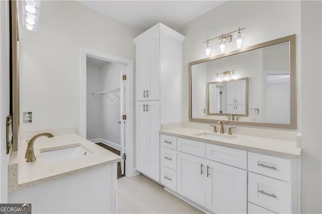 bathroom featuring a walk in closet, two vanities, and a sink