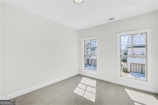 carpeted spare room featuring baseboards and visible vents