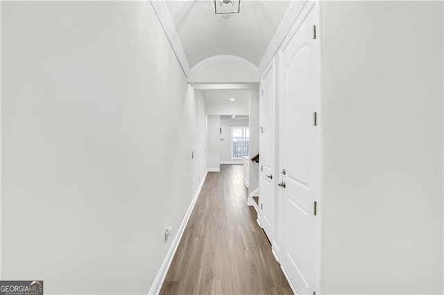 hallway with crown molding, baseboards, and wood finished floors